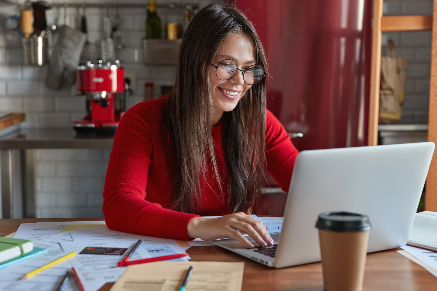 Image by Freepik https://www.freepik.com/free-photo/glad-professional-brunette-female-accountant-makes-distant-work-keyboards-laptop-computer-sits-kitchen-table-with-papers-wears-transparent-glasses-good-vision-drinks-coffee-go_12203342.htm#fromView=search&page=1&position=10&uuid=c26ab567-8835-4710-9576-df282e6c1e36&query=business+blog+writer+smiling