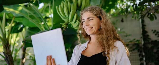 https://www.pexels.com/photo/photo-of-a-woman-with-a-laptop-standing-against-a-banana-plant-4458358/